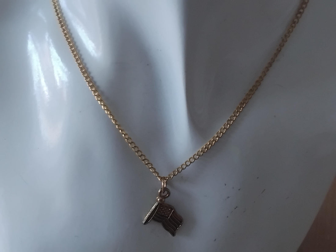 Gold necklace with an American flag pendant on a white background