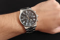 Wristwatch with black dial and silver case on a dark background